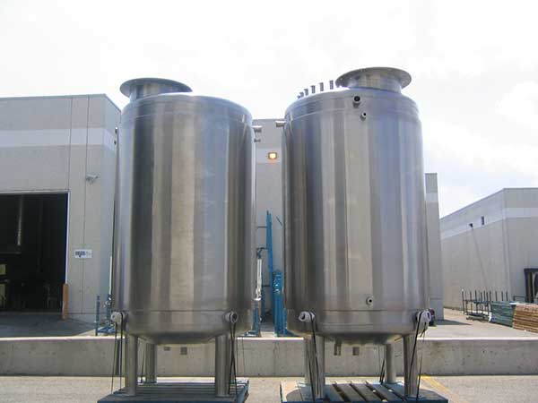 Two large stainless steel industrial storage tanks installed outdoors