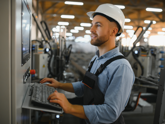 Factory worker operating a machine control panel with a keyboard.